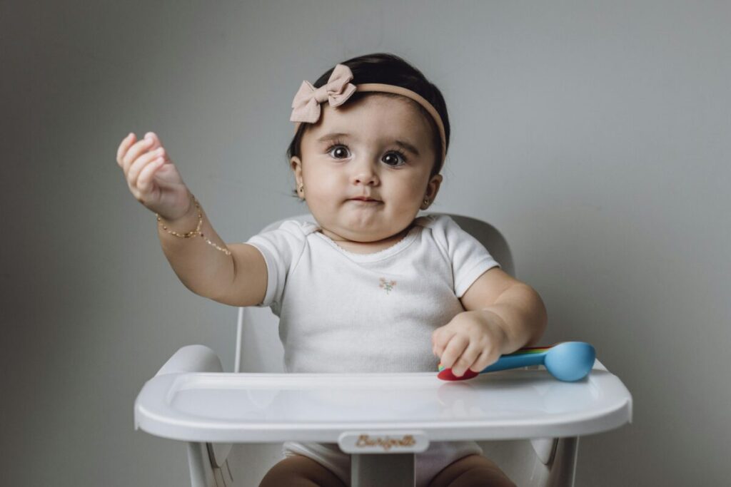 Happy baby in a high chair ready for early allergen introduction with healthy egg breakfast.