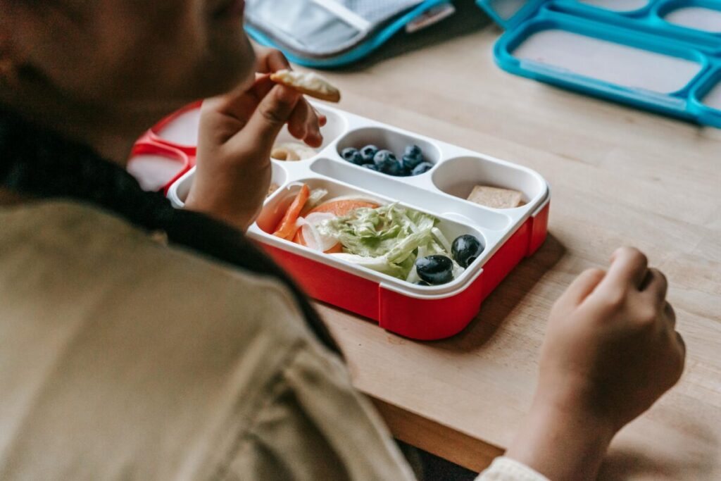 A toddler looking disappointed at their lunchbox, illustrating the frustration of picky eating and food refusals.