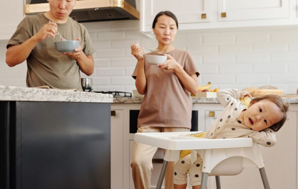 A parent attentively watching a 6-month-old baby during mealtime to observe for any potential allergic reactions